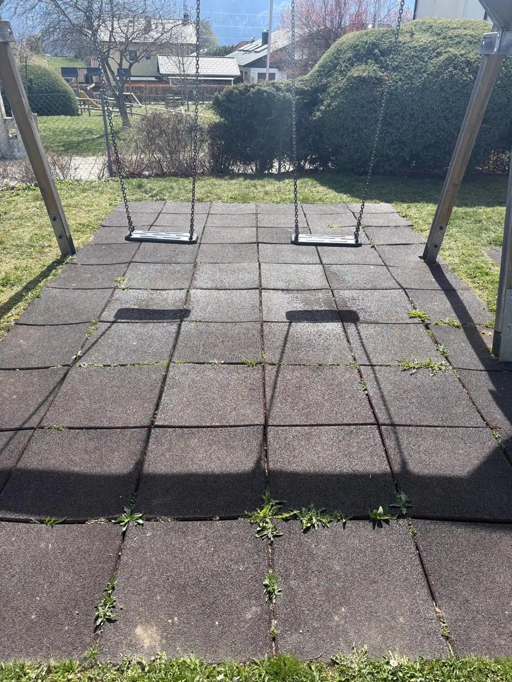 Vorher: Spielplatz mit Moos und Bewuchs auf Fallschutzplatten vor der Spielplatzreinigung